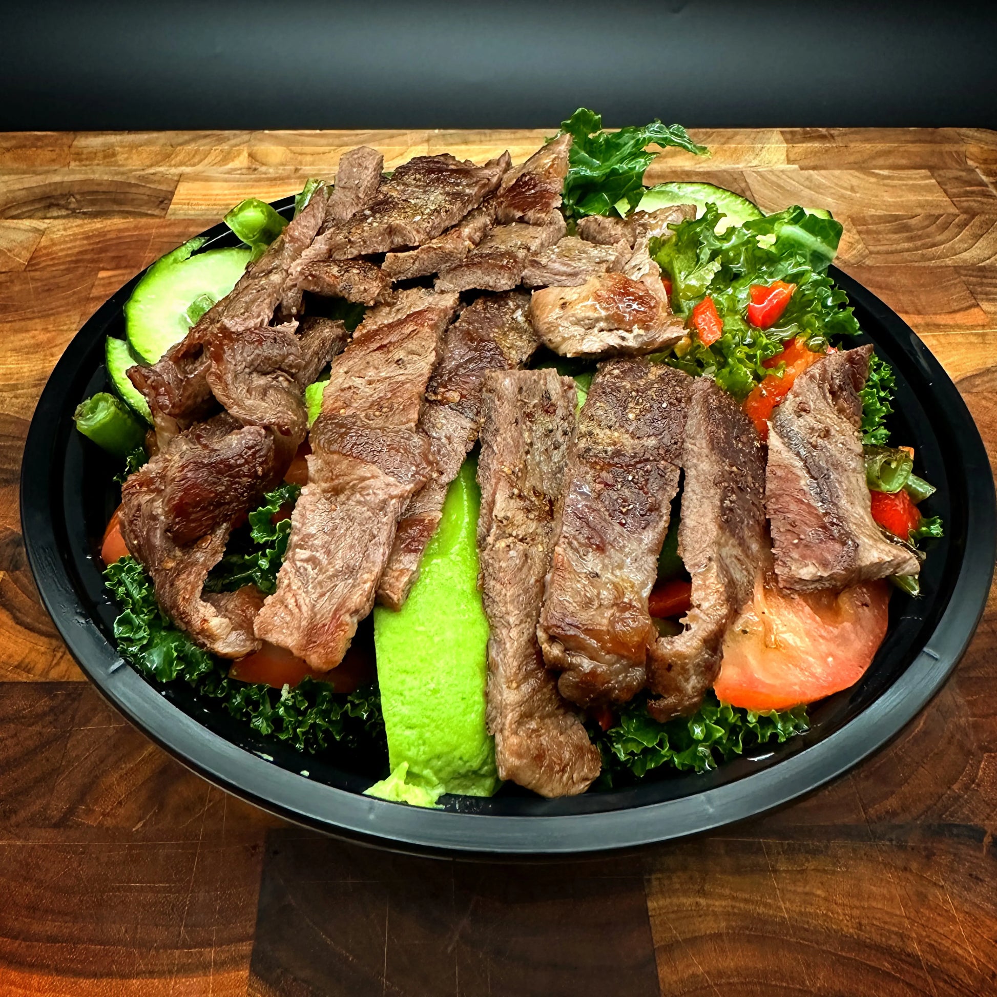 Steak Keto Bowl with Flat Iron Steak, asparagus, bell pepper, cucumber, tomato, kale, and avocado.