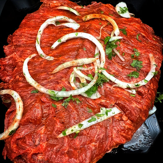 Marinated Carne Asada - Thinly sliced prime sirloin flap steak, marinated in a citrus blend with herbs and spices, ready for grilling.