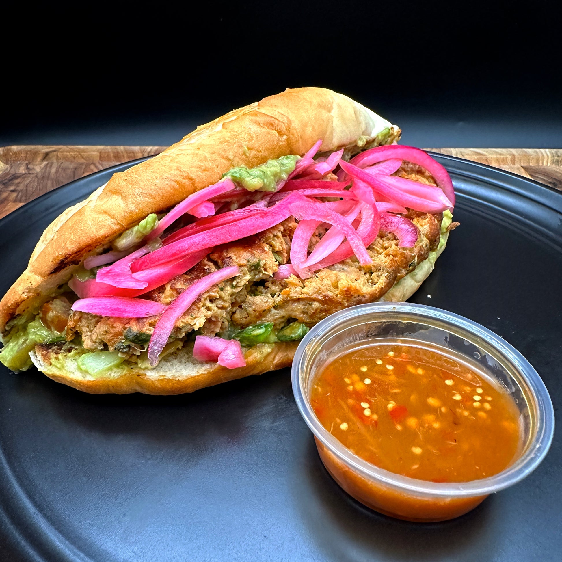 Chicken habanero choripan with in-house sausage, guacamole and pickled onions on bolillo roll with seasoned fries