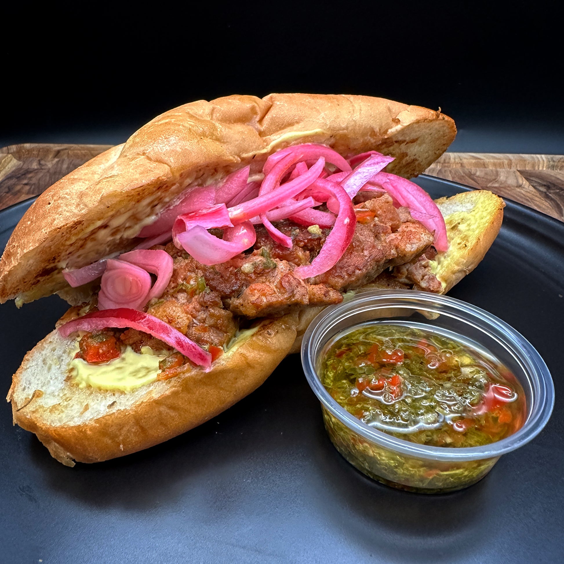 Roberto's Argentine style choripan with in-house sausage, chimichurri and pickled onions on a bolillo roll with seasoned fries