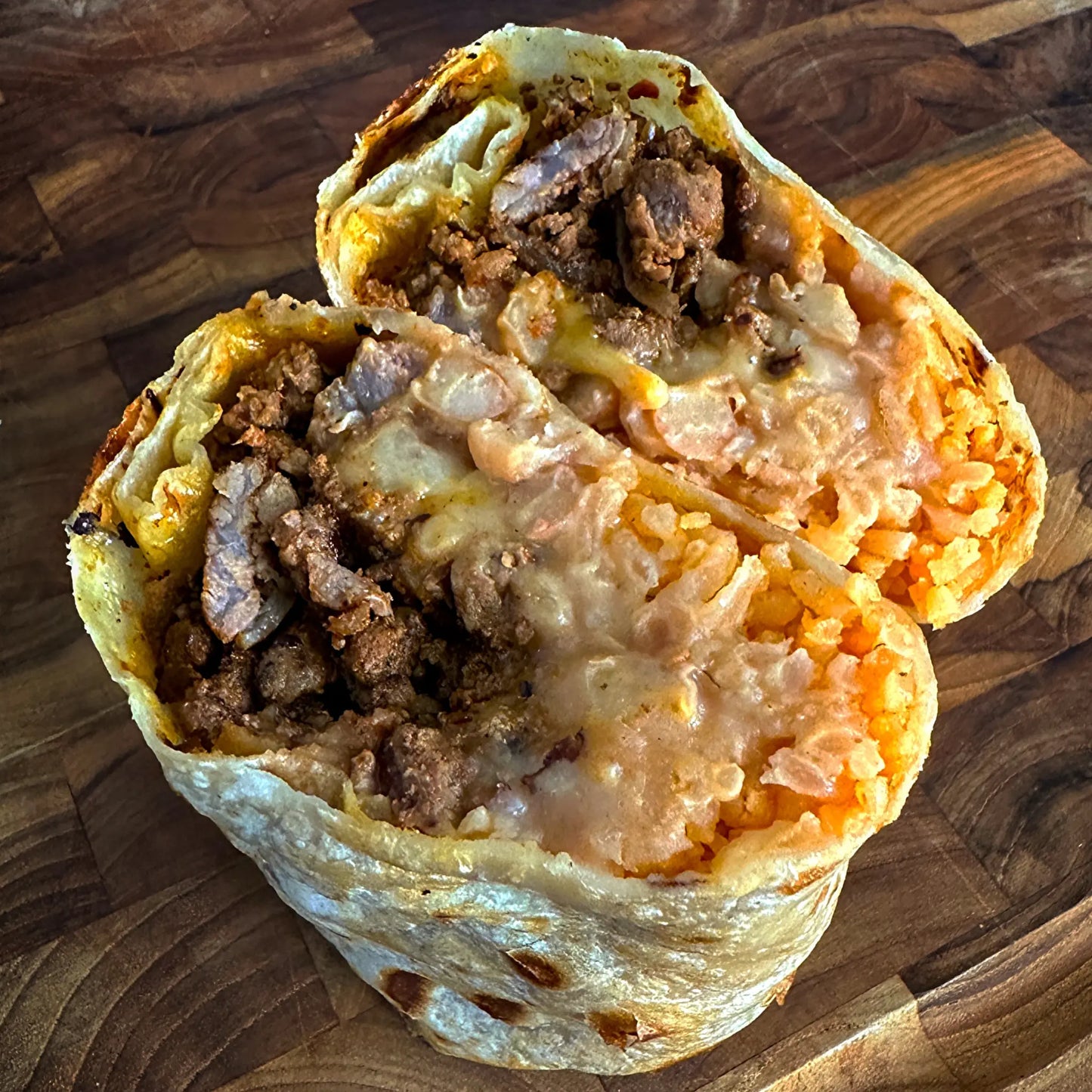 Hearty burrito filled with meat, rice, beans, and cheese in a giant flour tortilla.