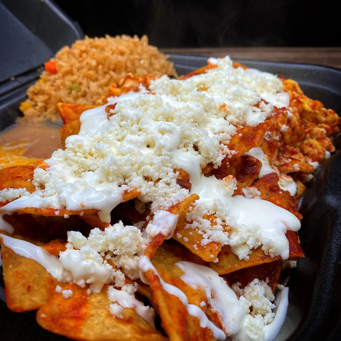 Chilaquiles with red or green salsa, queso fresco, sour cream, rice, and beans.