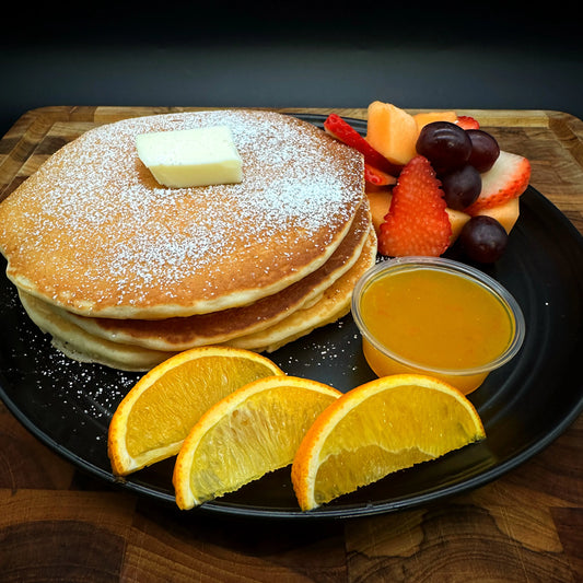Orange Pancakes with orange syrup, butter, and seasonal fruit.